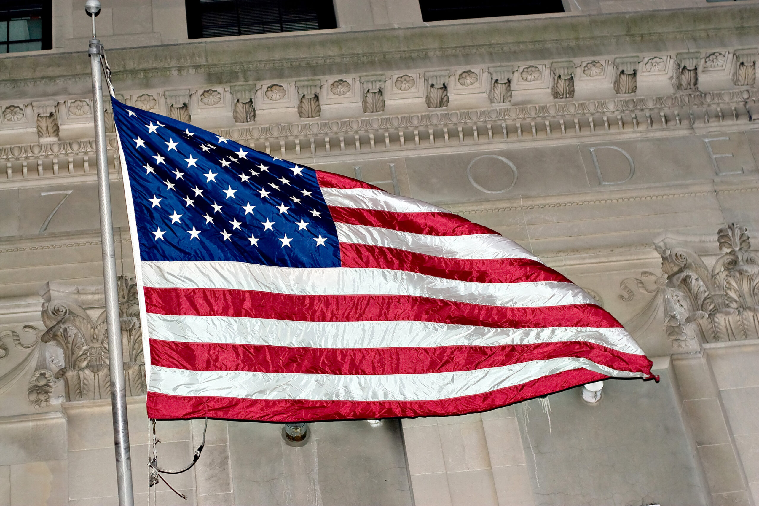 An American flag flying in front of some classic architecture.