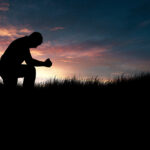 Man praying in the grassy field